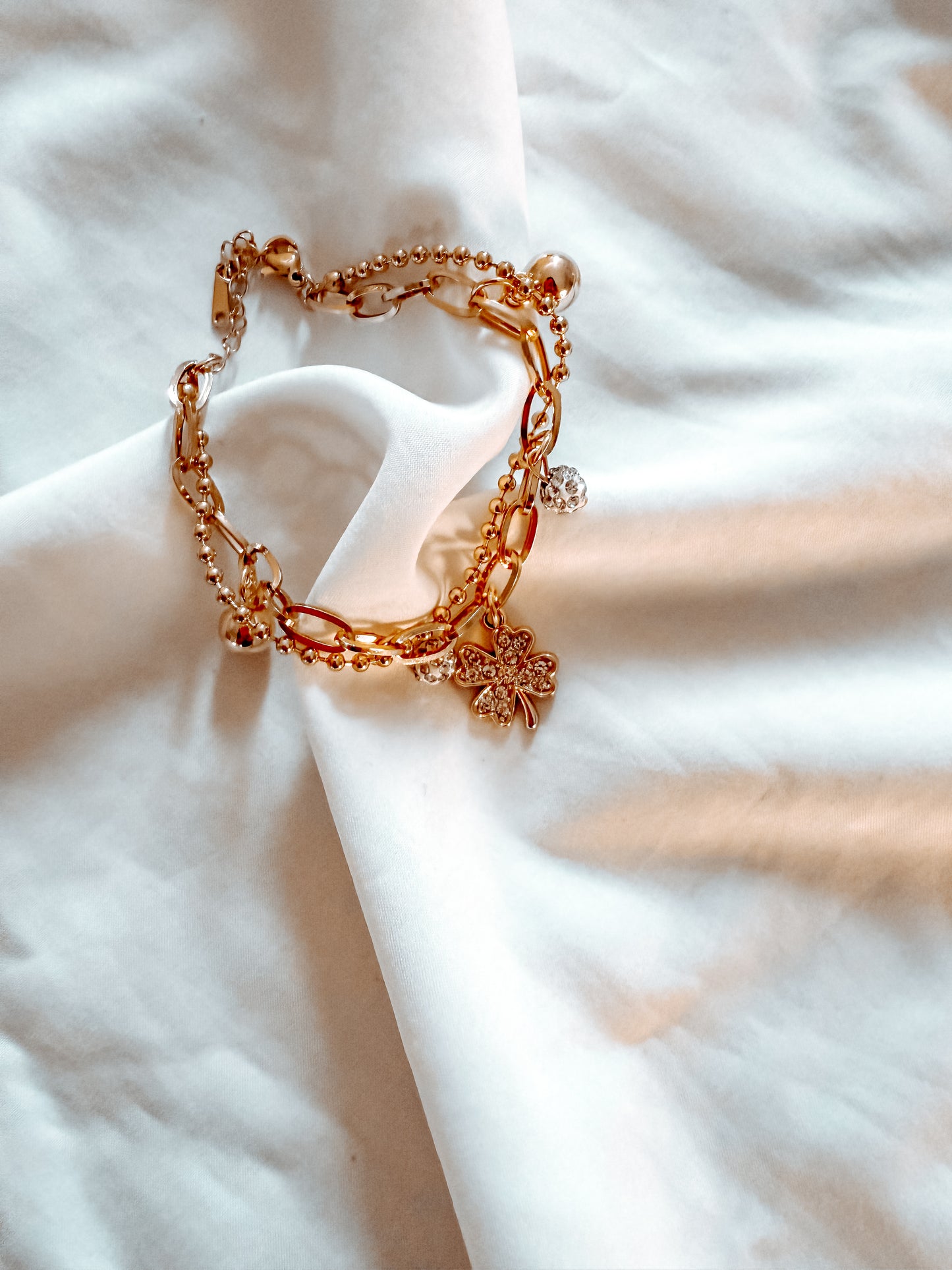 Bracciale “Tessa” in acciaio inox, con doppia catena e ciondoli. Color oro.